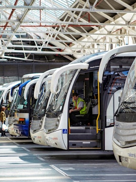Coaches lined up at Gatwick Airport terminal with a driver inside one vehicle.