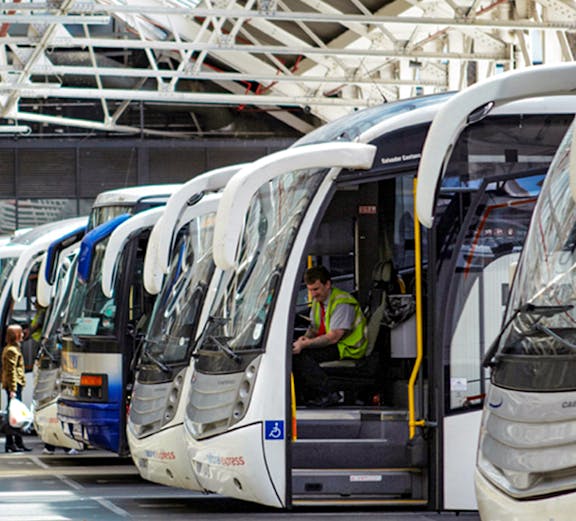 Coaches lined up at Gatwick Airport terminal with a driver inside one vehicle.