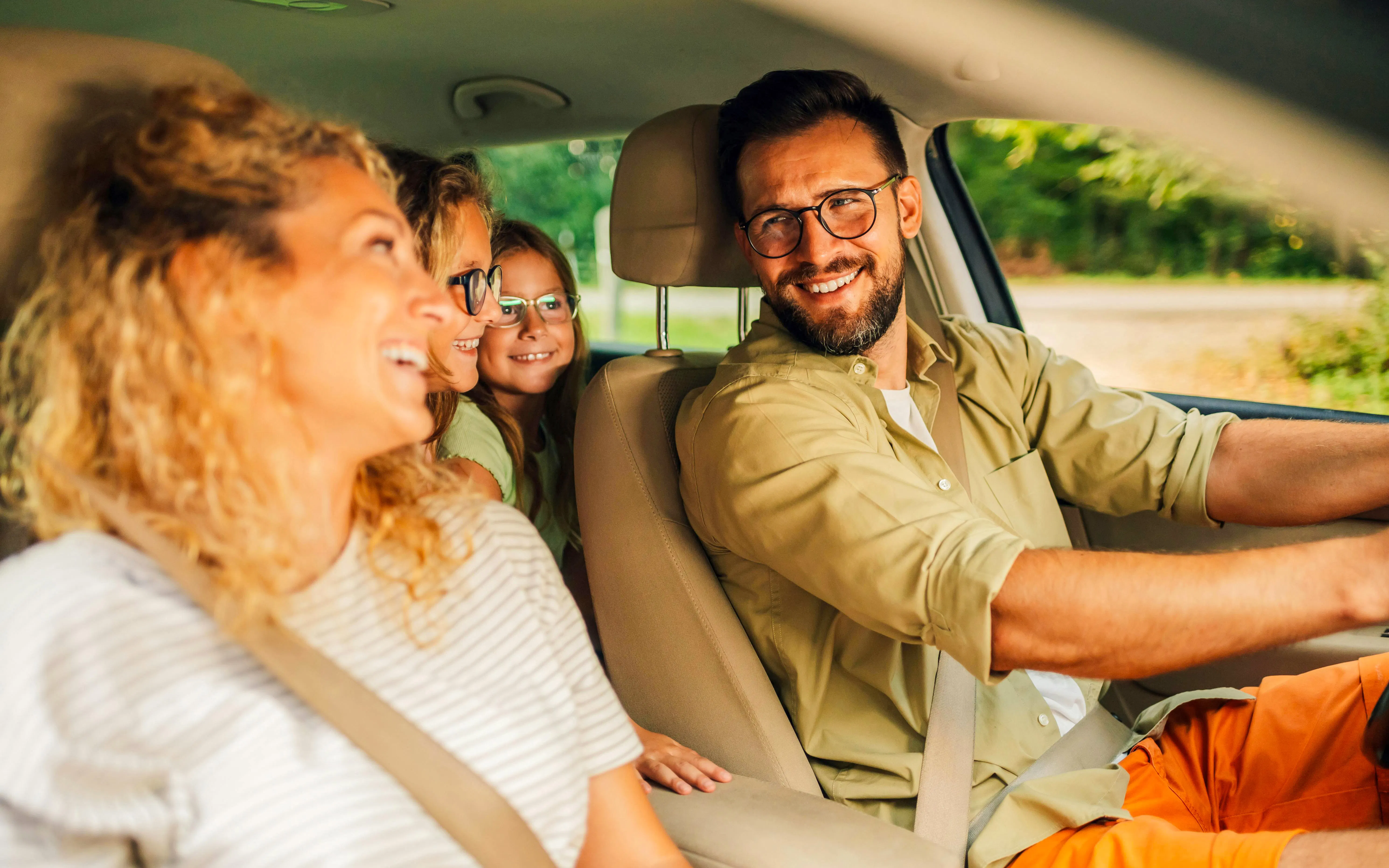 Family smiling in a car on a road trip to Disneyland Paris.