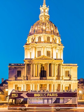 Big Bus Paris in front of Les Invalides dome at night.