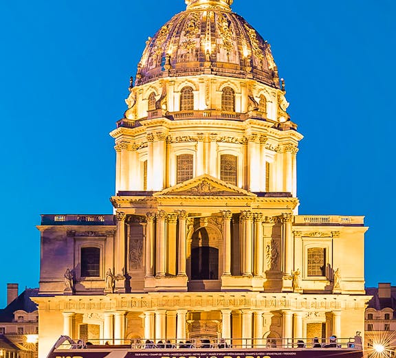 Big Bus Paris in front of Les Invalides dome at night.