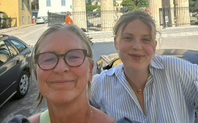 Two people smiling in front of ancient columns in Plaka, Athens during a self-guided city exploration game.