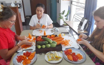 Participants carving fruits and vegetables in a Thai class with Master Carver Wan Hertz in a penthouse studio.