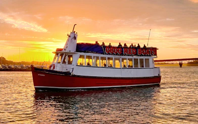 Auckland Harbour cruise boat at sunset with city skyline in background.