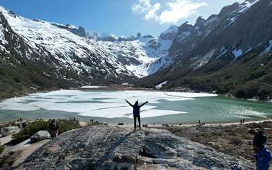 Trekker at Esmeralda Lake with snow-capped mountains in Tierra del Fuego, Argentina.