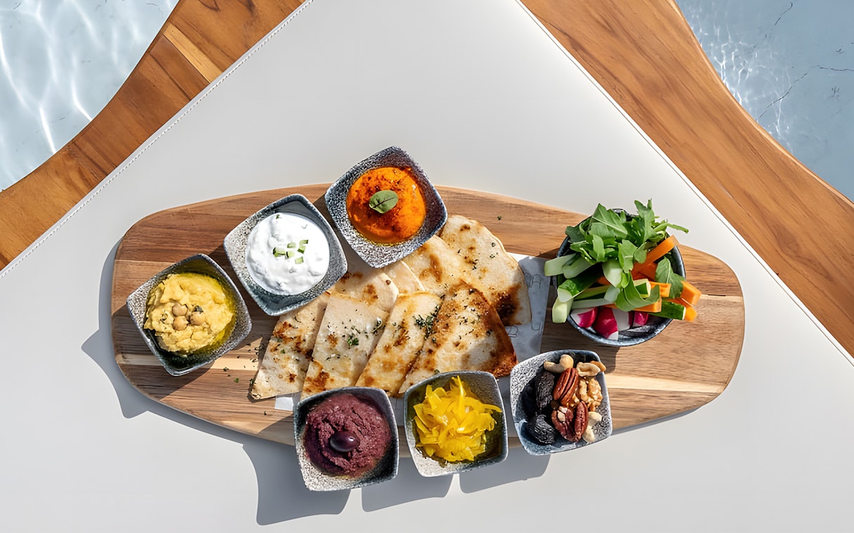 Assorted dips and flatbreads on a wooden platter at Yona Beach Club, Phuket.