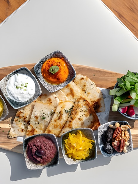 Assorted dips and flatbreads on a wooden platter at Yona Beach Club, Phuket.