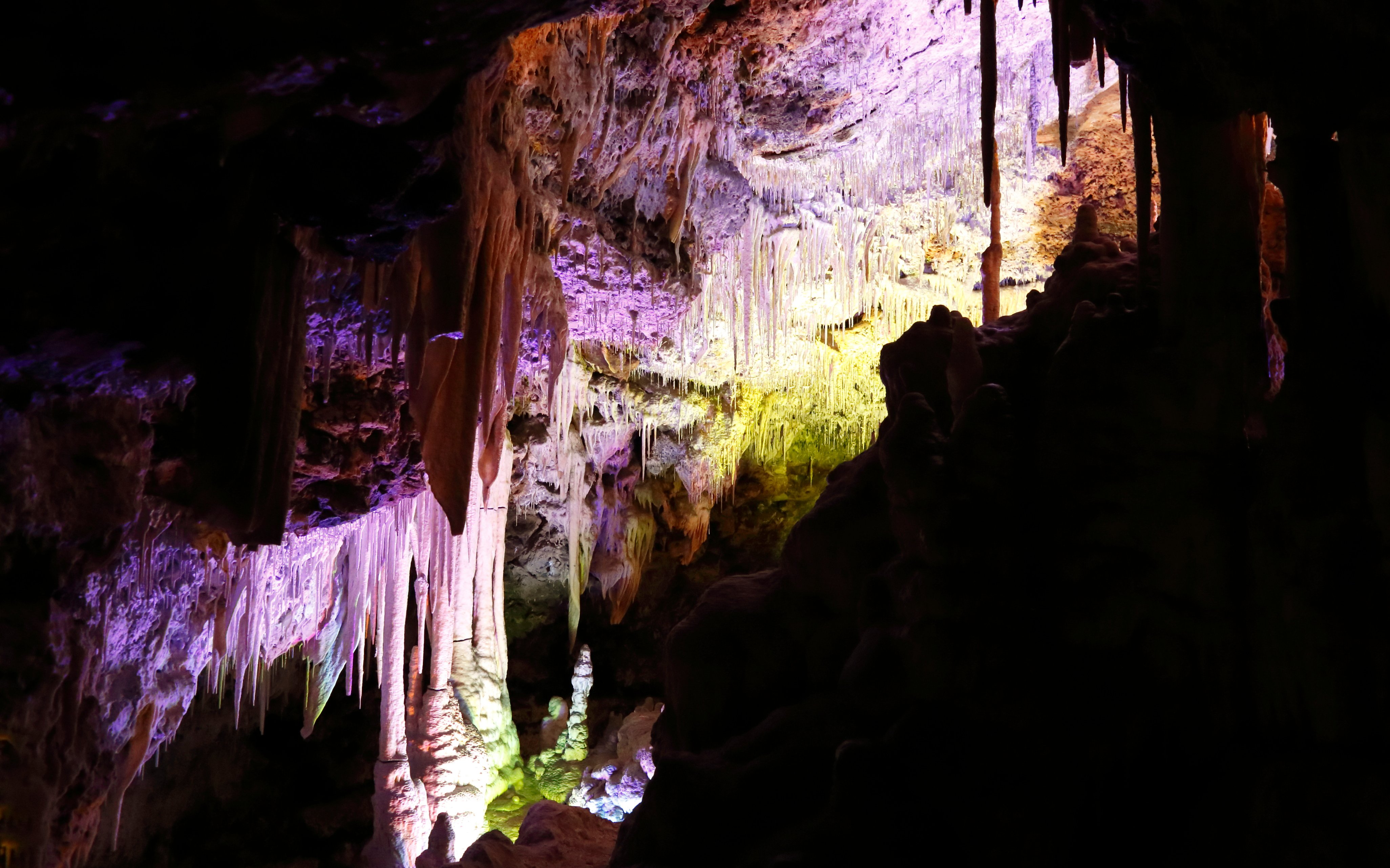 Stalactites and stalagmites inside Drach Caves, Mallorca, illuminated with colorful lights.