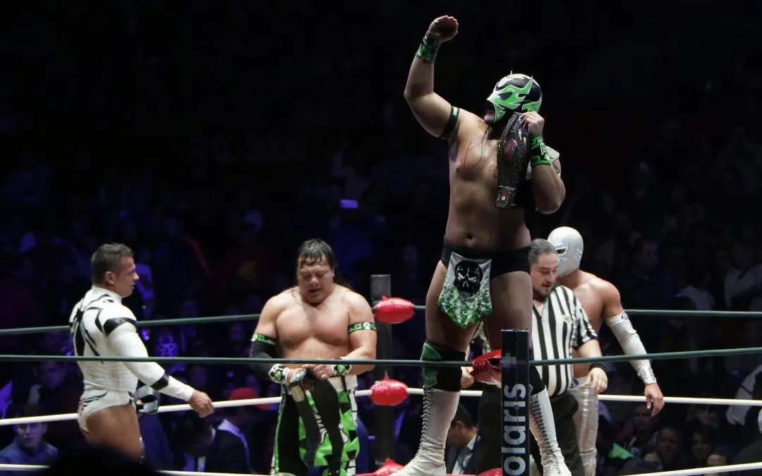 Wrestlers in colorful masks and costumes in a match at Lucha Libre Arena Mexico.