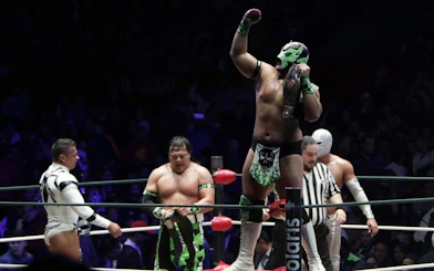 Wrestlers in colorful masks and costumes in a match at Lucha Libre Arena Mexico.
