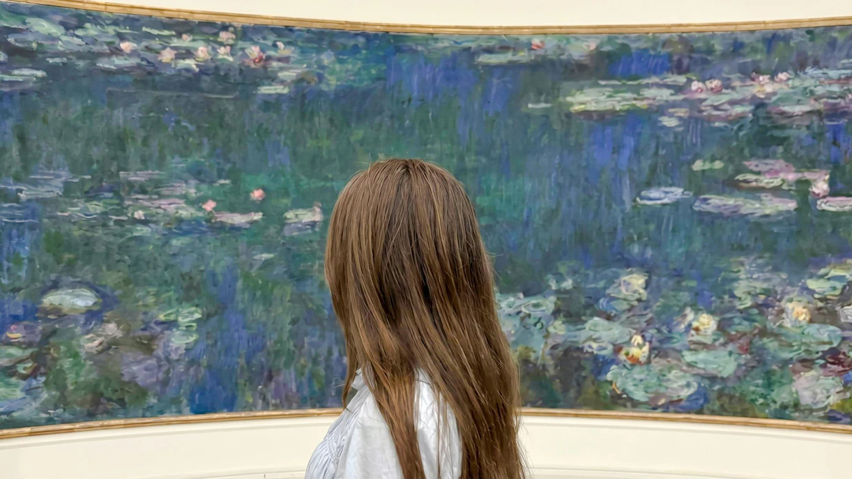 Visitor admiring Monet's Water Lilies at Musée de l’Orangerie, Paris.