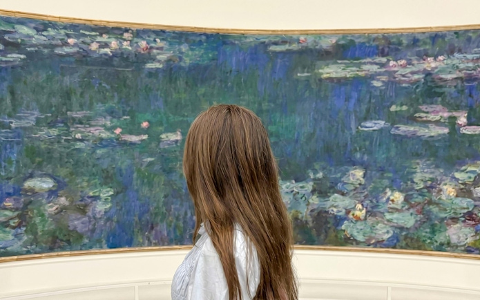 Visitor admiring Monet's Water Lilies at Musée de l’Orangerie, Paris.