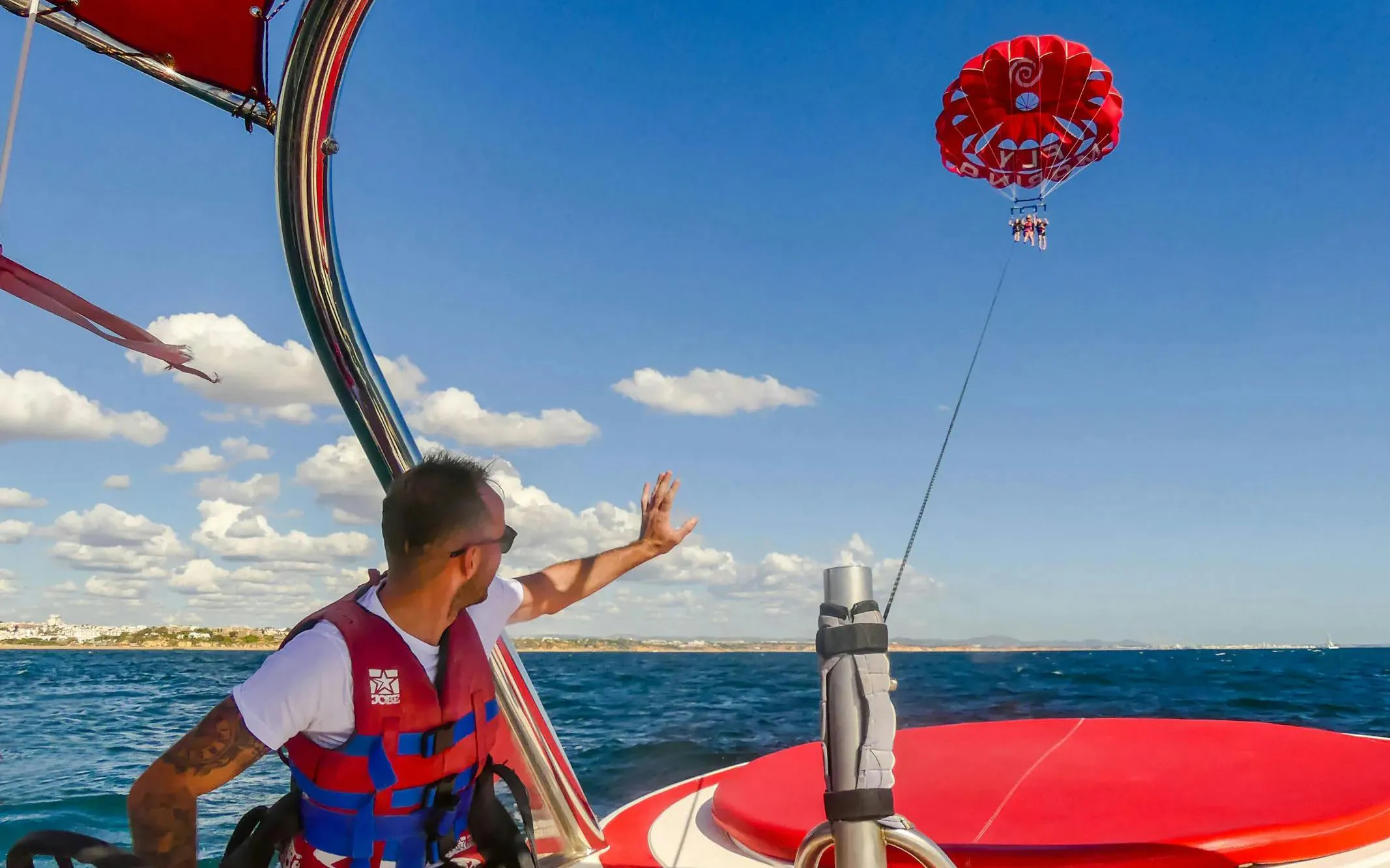 Parasailing over the ocean in Albufeira with a guide on the boat.