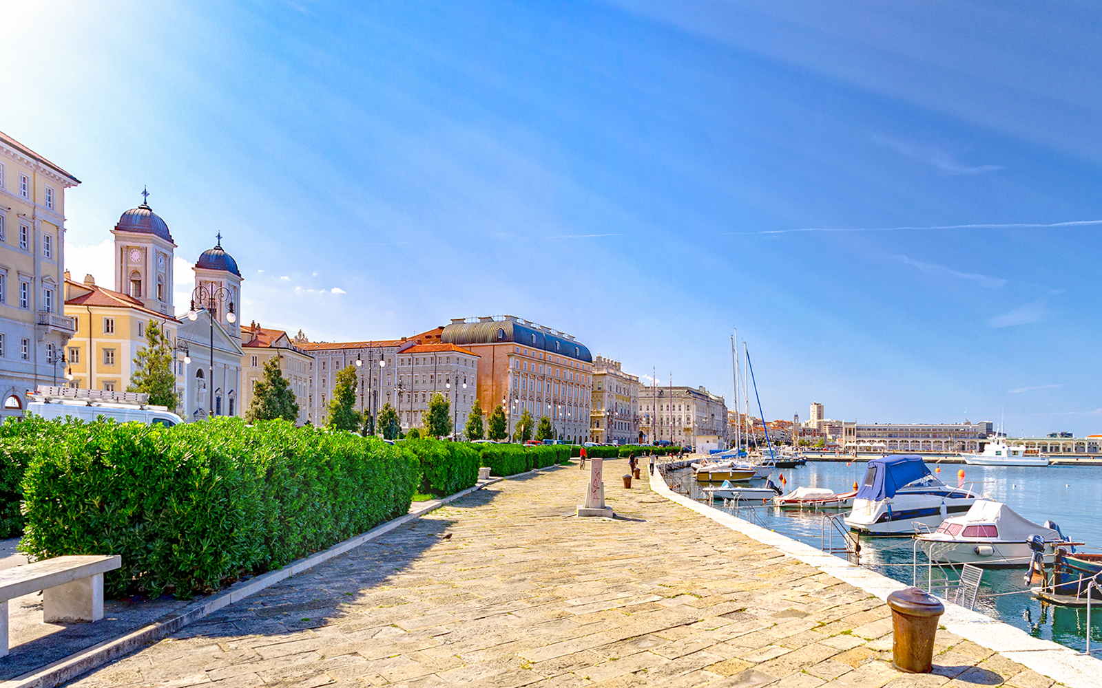Trieste waterfront promenade with historic buildings and boats by the Adriatic Sea, Italy.