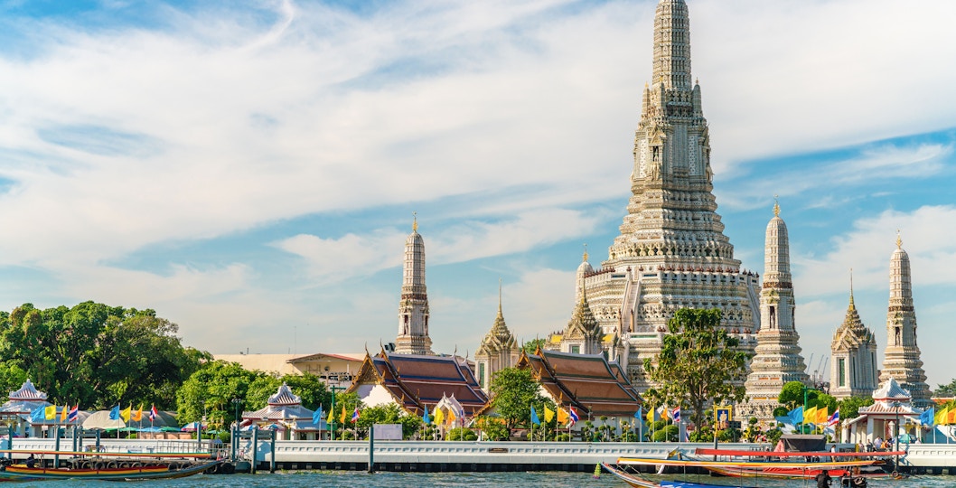 Boat on Chao Phraya River with Wat Arun temple in Bangkok, Thailand.