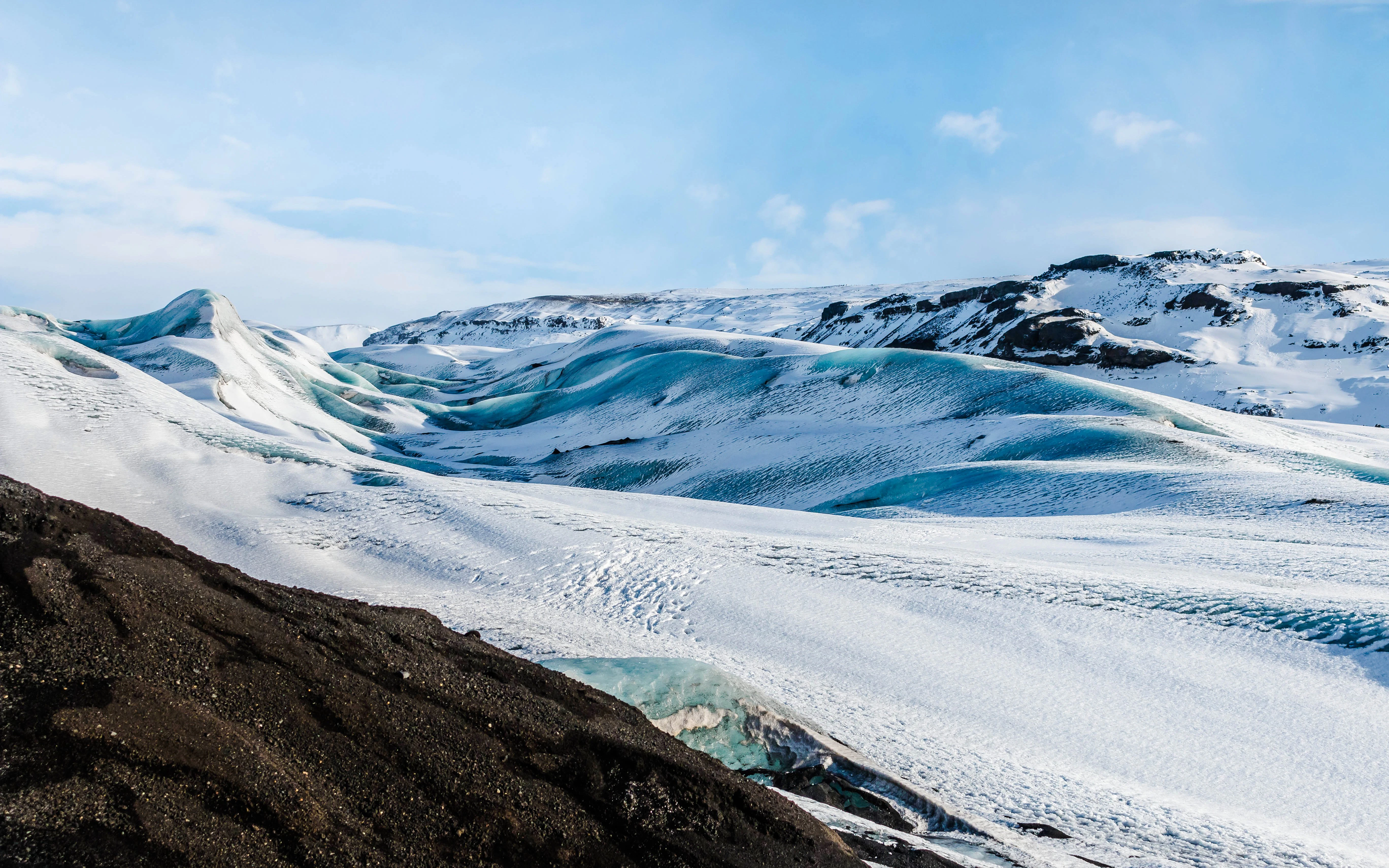 Myrdalsjokull glacier in Iceland with snow-covered peaks and blue ice formations.