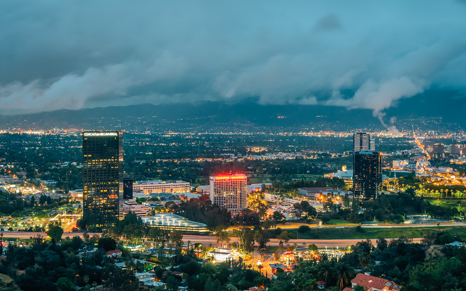 Night view of Los Angeles cityscape from Universal City Overlook with illuminated buildings.