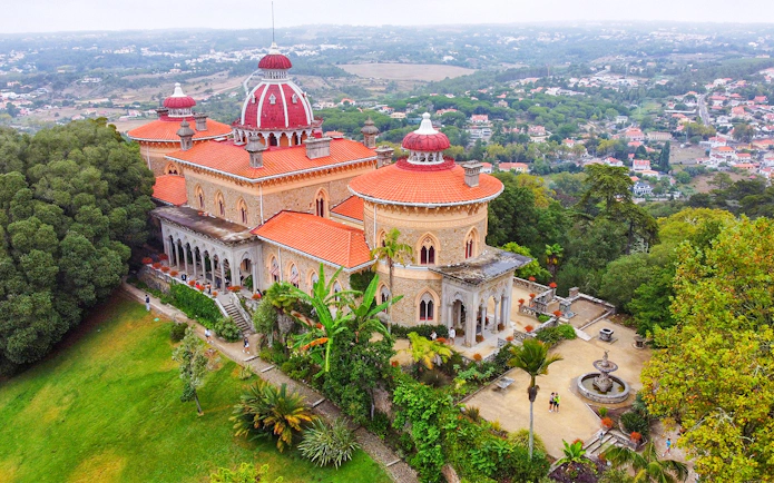 Aerial view of Monserrate Palace in Sintra, Portugal, surrounded by lush gardens and greenery.