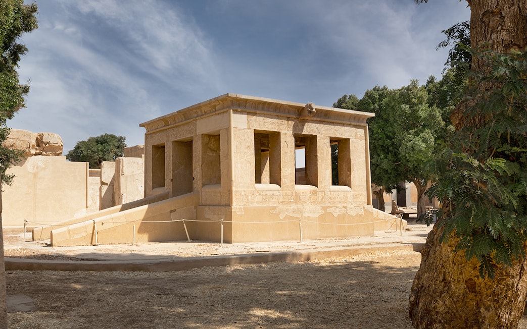 Karnak Temple ruins with hieroglyphs, surrounded by trees, Luxor, Egypt.