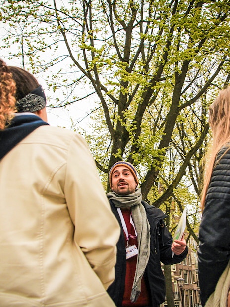 Tour guide speaking to group near statue during Amsterdam winter walking tour.