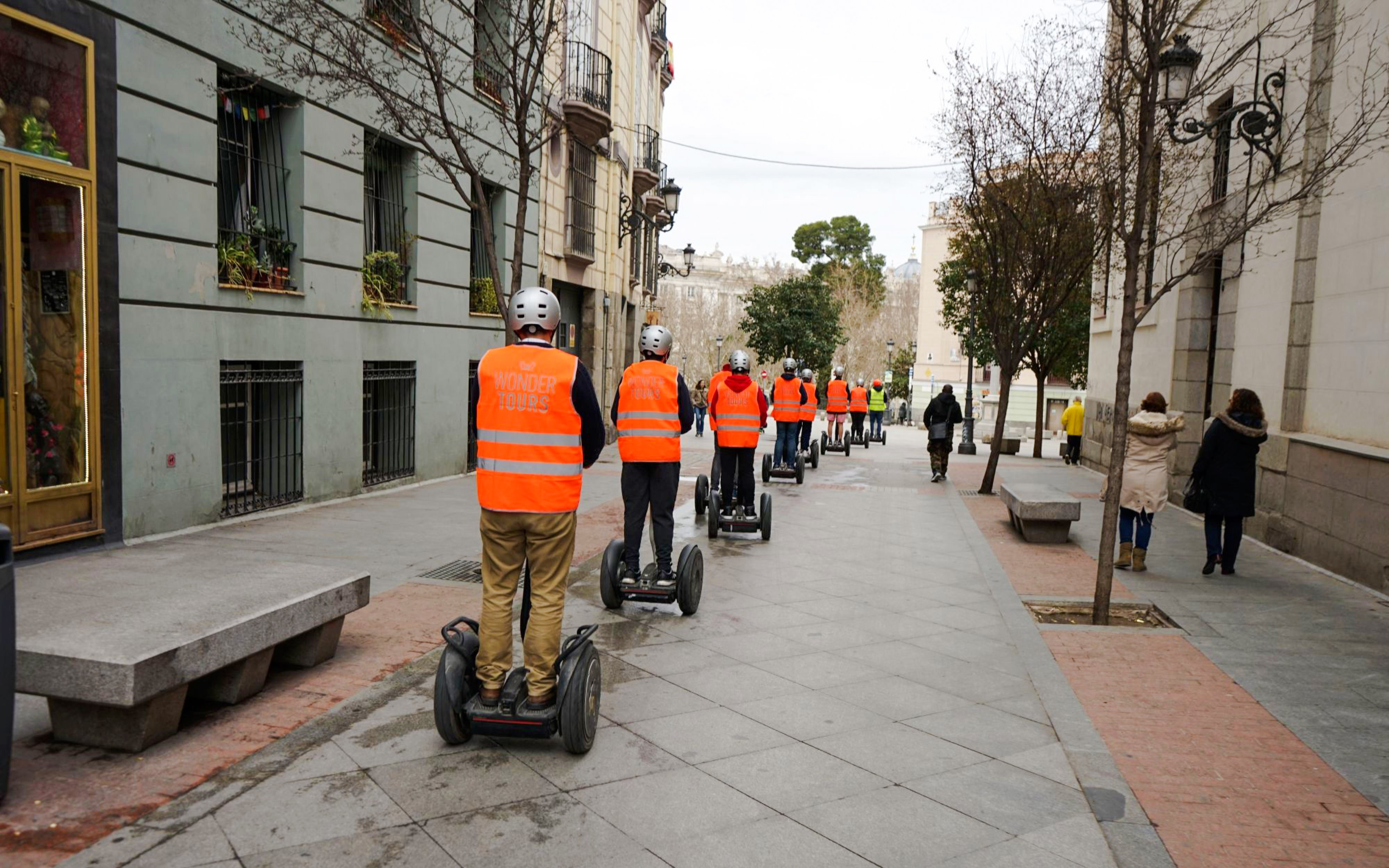 Group on Segway tour in city street wearing orange vests.
