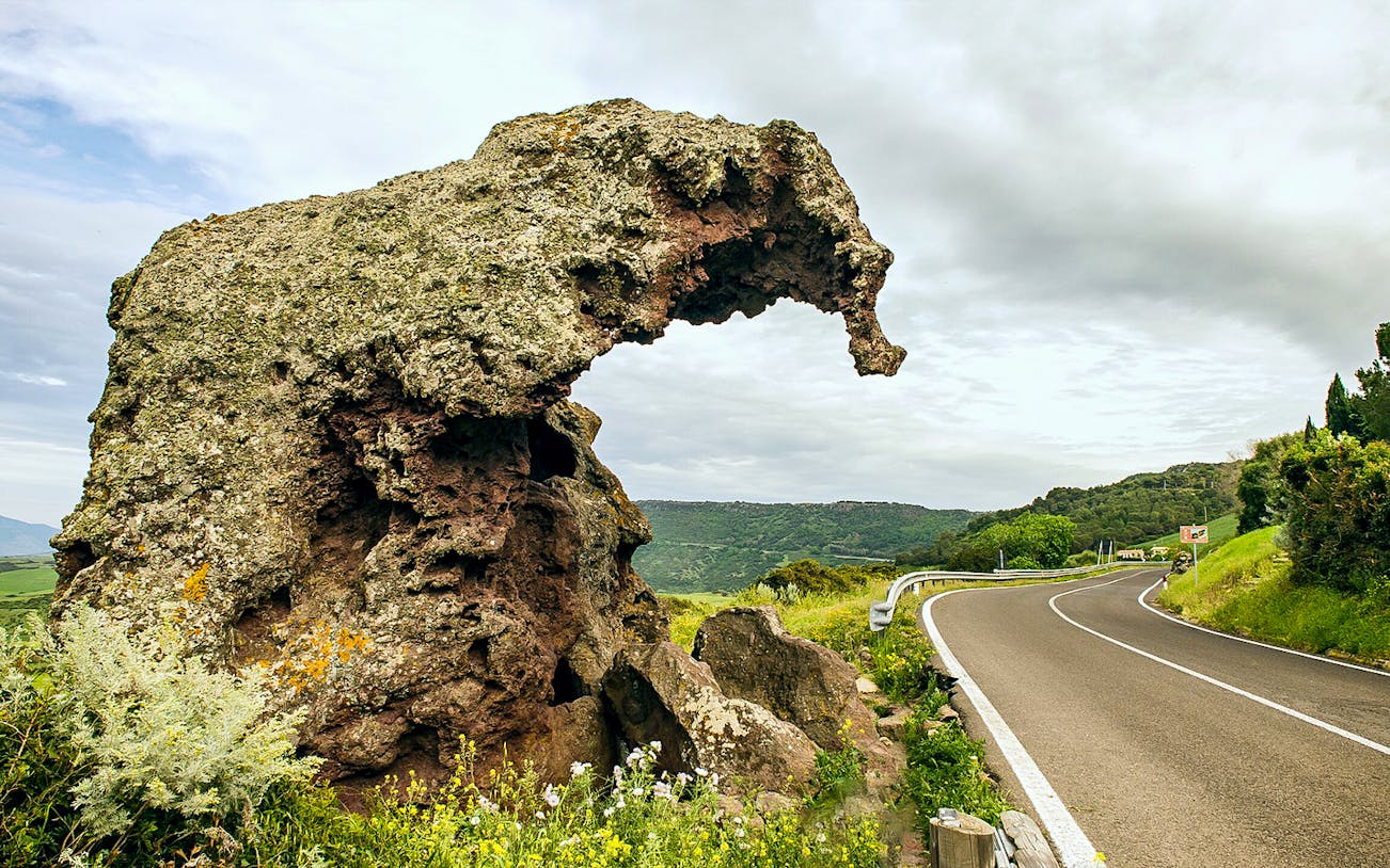 Curved rock formation near a winding road in Castelsardo, Sardinia.