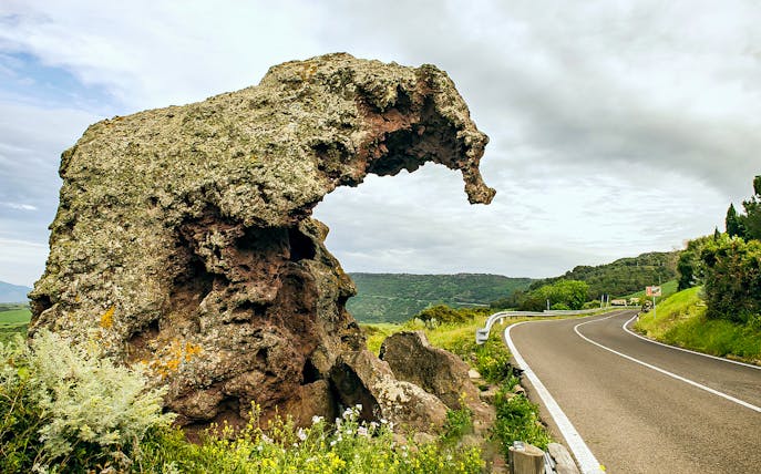 Curved rock formation near a winding road in Castelsardo, Sardinia.