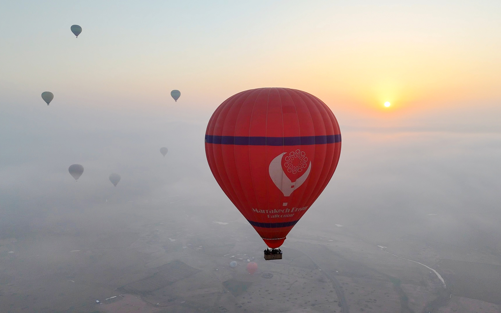Hot air balloons floating over Marrakech at sunrise.