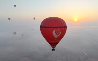 Hot air balloons floating over Marrakech at sunrise.