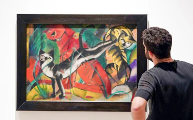 Visitor admiring a colorful painting of cats at Picasso Museum, Malaga.