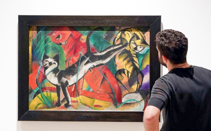 Visitor admiring a colorful painting of cats at Picasso Museum, Malaga.