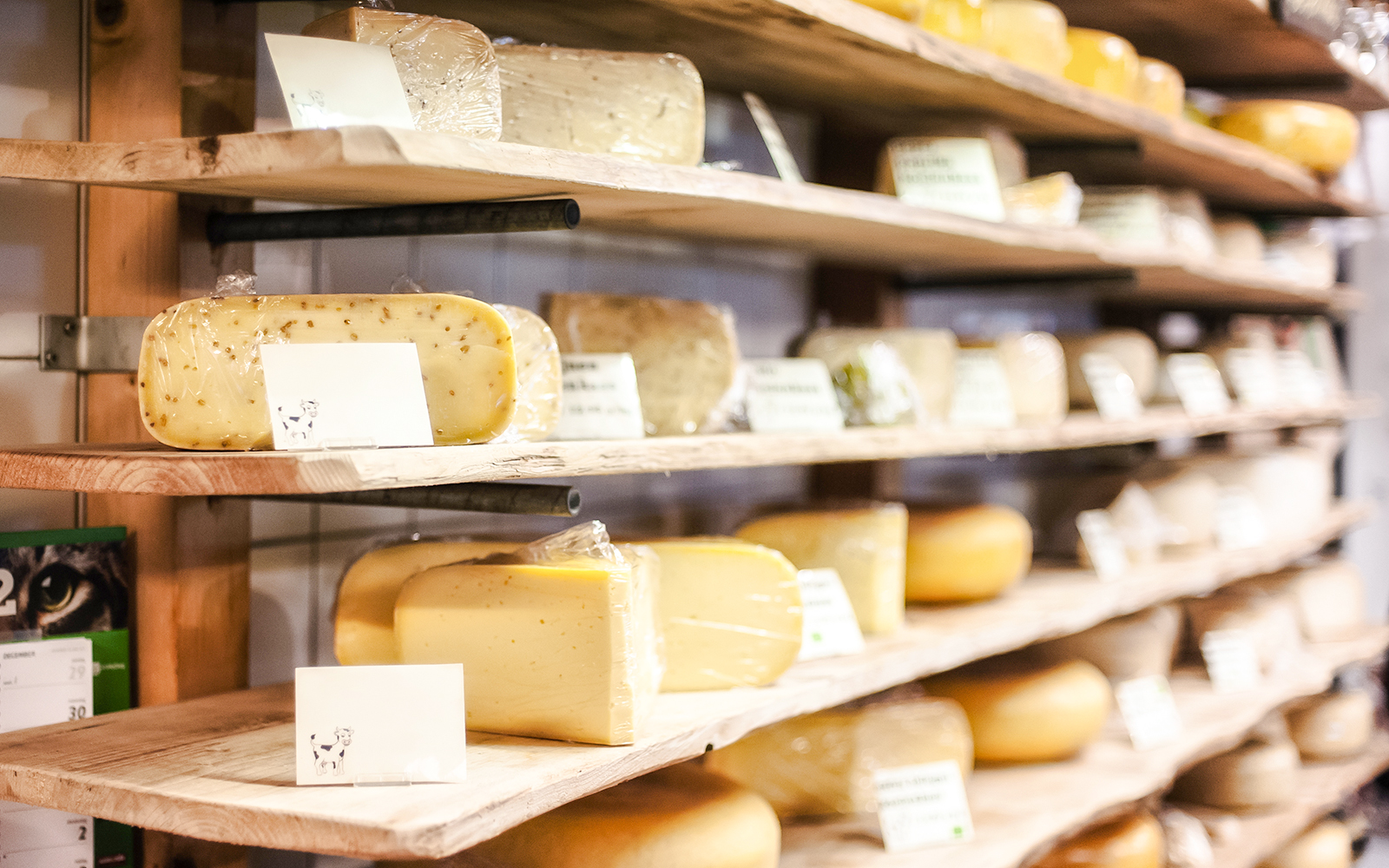Assorted cheeses on wooden shelves at Cheese Museum in Paris.