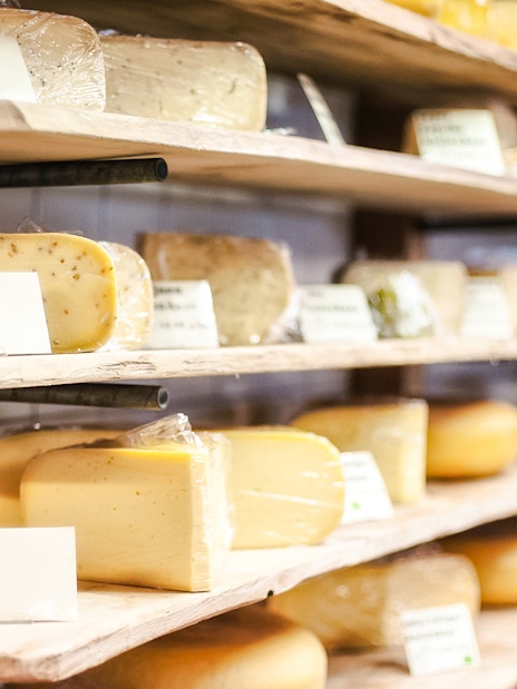 Assorted cheeses on wooden shelves at Cheese Museum in Paris.