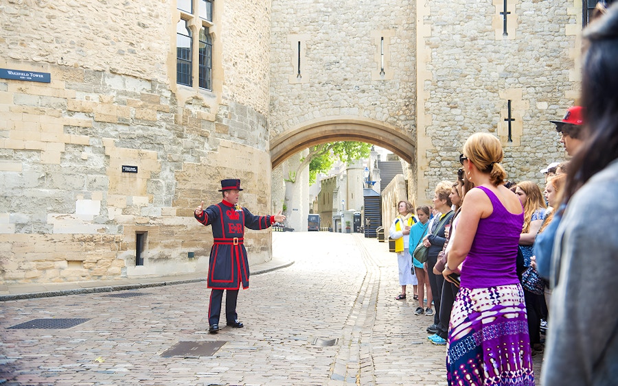 Tower of London Beefeater greeting visitors during early morning guided tour.