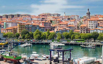 Boats docked at the port of Mundaka, Spain with colorful buildings in the background.