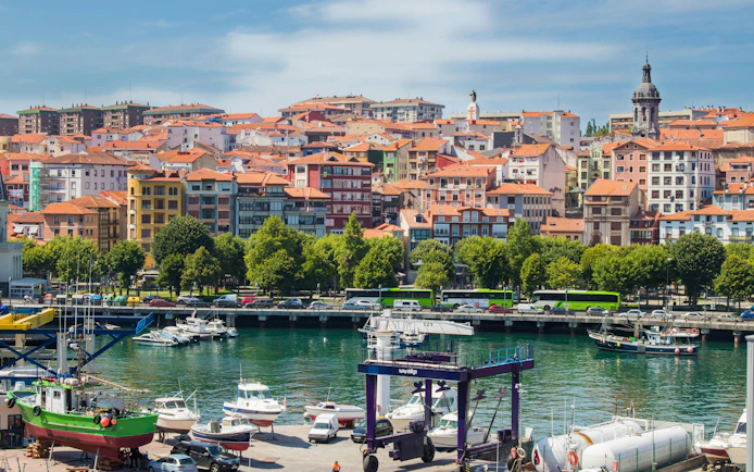 Boats docked at the port of Mundaka, Spain with colorful buildings in the background.
