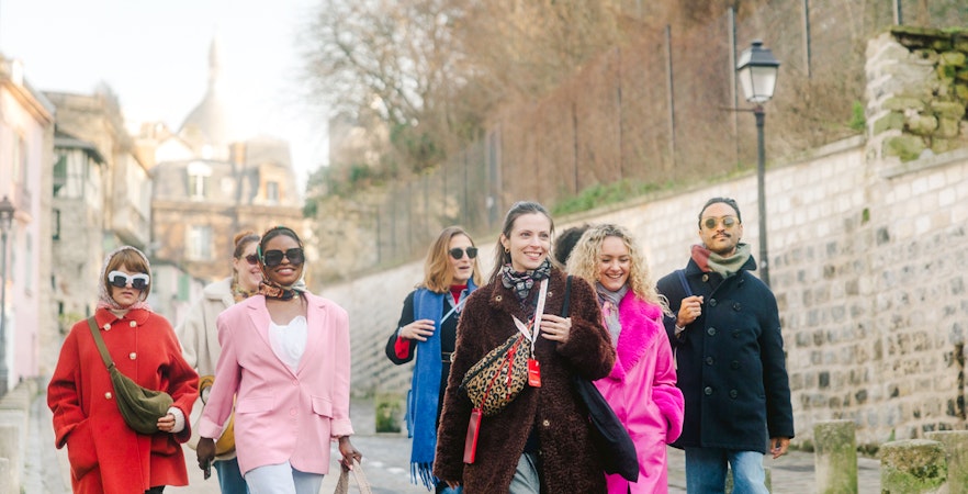 Group walking in Montmartre, Paris, with Sacré-Cœur in the background on a guided tour.