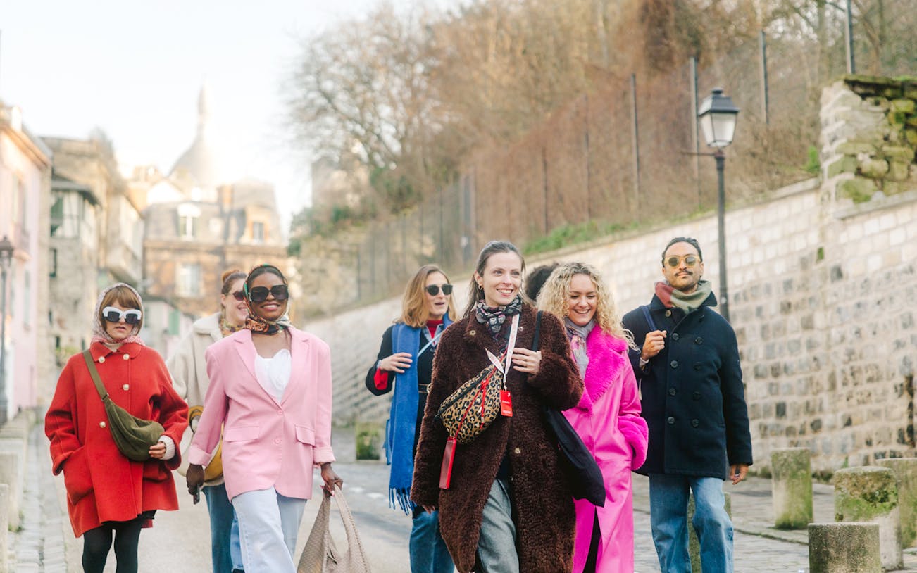 Group walking in Montmartre, Paris, with Sacré-Cœur in the background on a guided tour.
