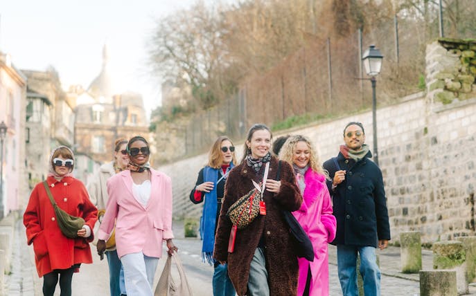 Group walking in Montmartre, Paris, with Sacré-Cœur in the background on a guided tour.