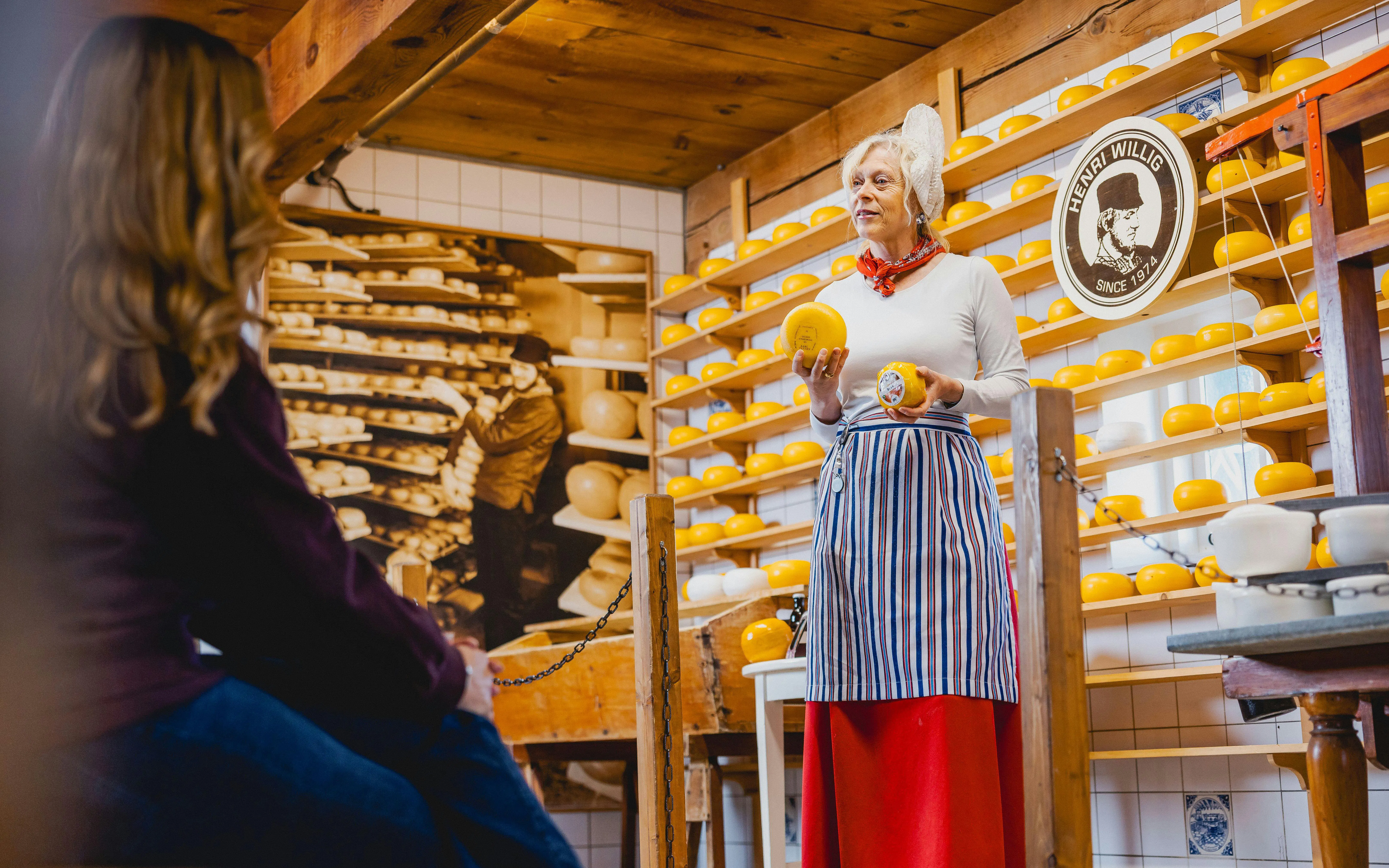 Cheese expert presenting Gouda wheels in a traditional Dutch cheese shop.