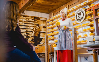 Cheese expert presenting Gouda wheels in a traditional Dutch cheese shop.