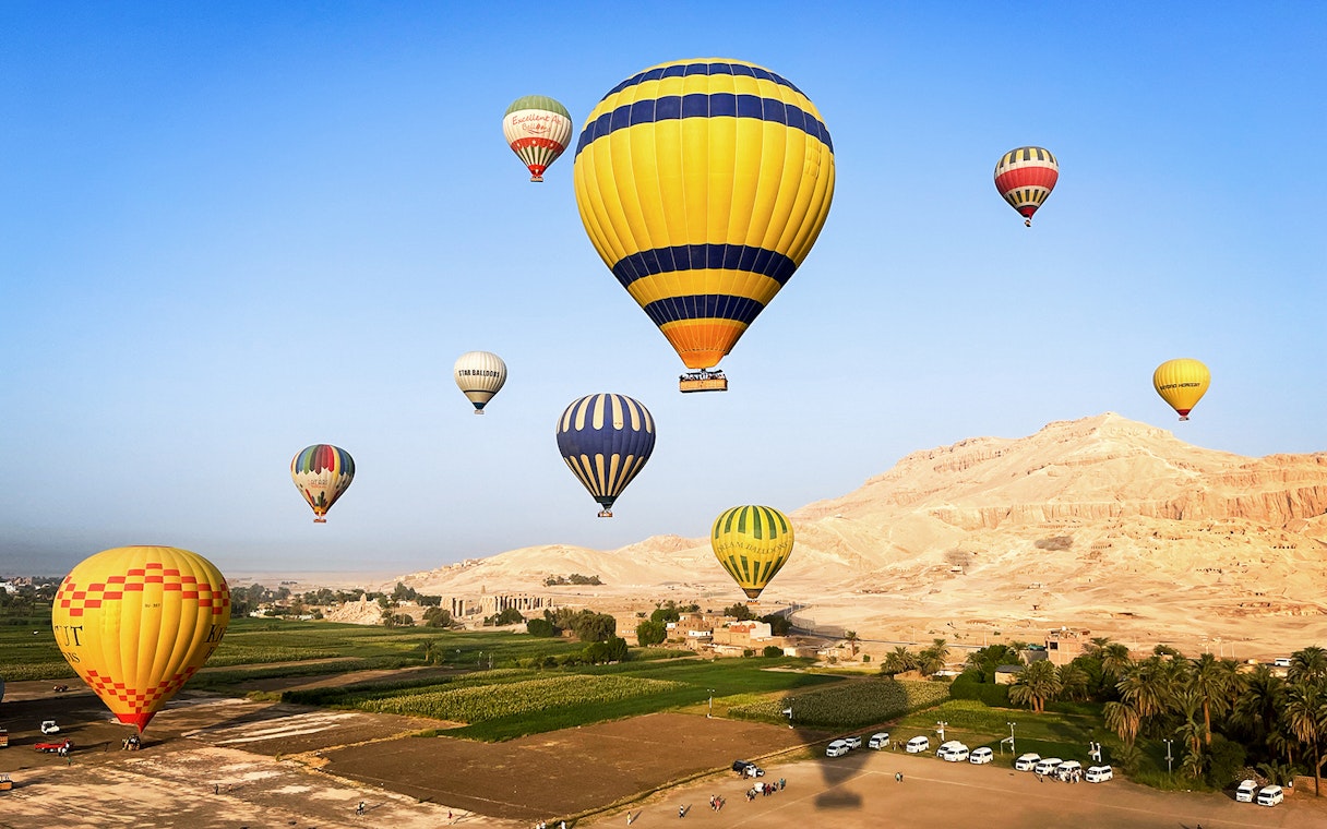 Hot air balloons floating over Luxor's desert landscape, Egypt.
