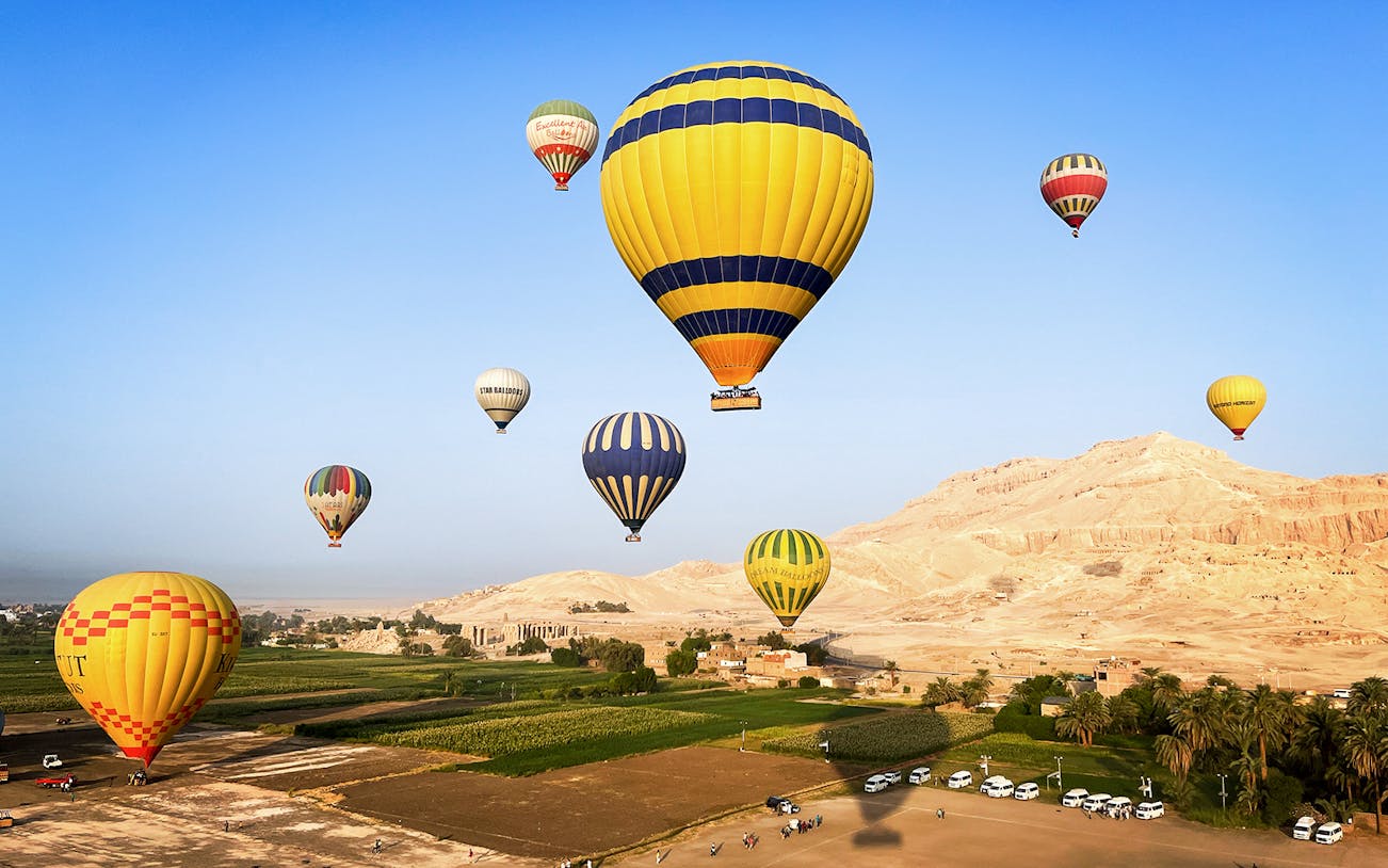 Hot air balloons floating over Luxor's desert landscape, Egypt.