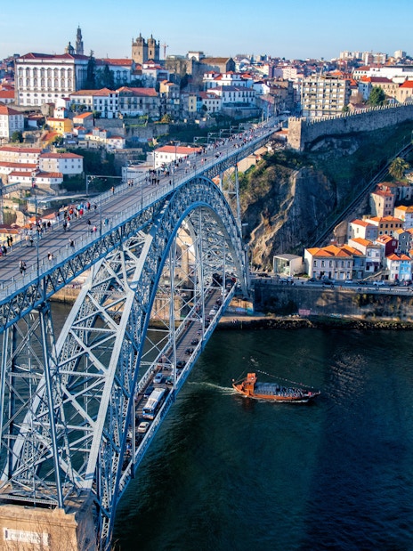 Dom Luís I Bridge spanning the Douro River in Porto, Portugal, with cityscape in the background.