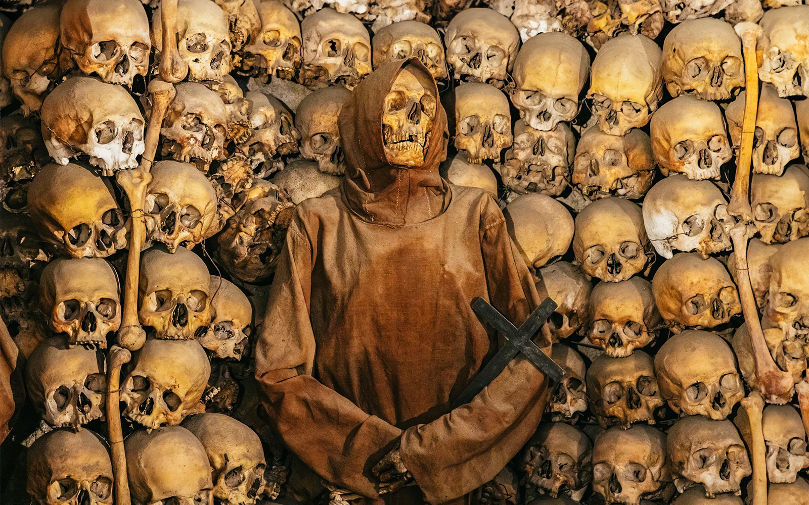 Skeleton in robe surrounded by skulls in Roman catacombs on the Appian Way.