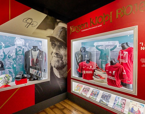 Liverpool FC memorabilia display featuring jerseys and trophies at Anfield Stadium Museum.