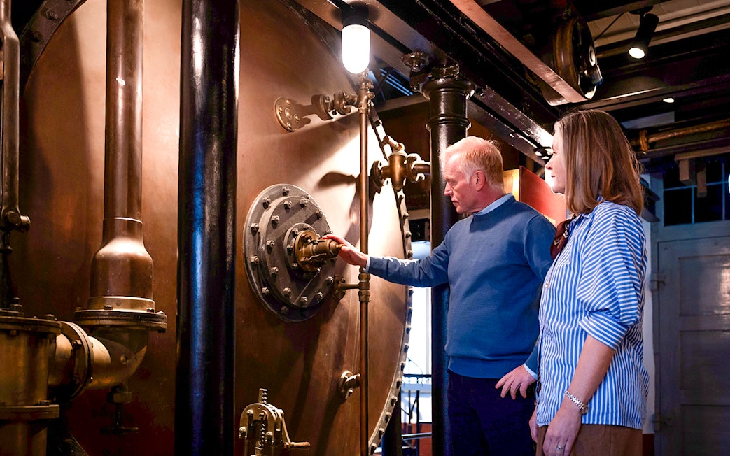 Guests examining brewing equipment in a brewery tour.