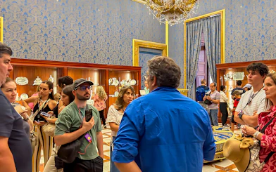Visitors on a guided tour inside the Royal Palace of Madrid, viewing ornate displays.