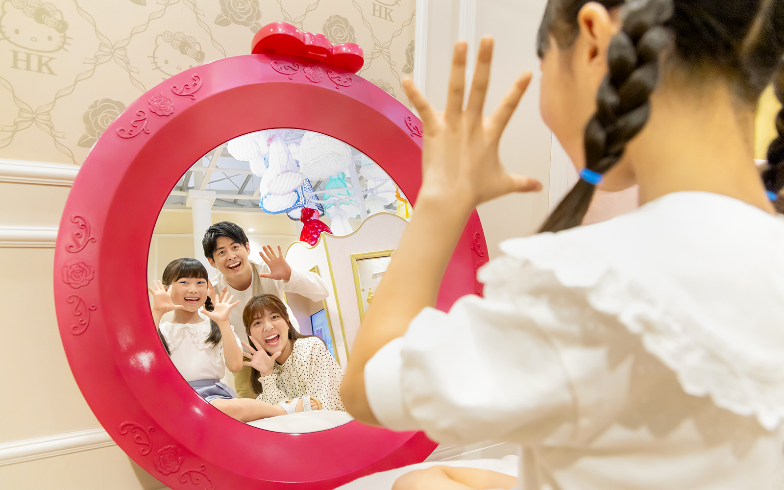 Family posing in a Hello Kitty-themed mirror at Sanrio Puroland.
