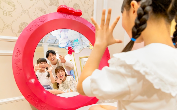 Family posing in a Hello Kitty-themed mirror at Sanrio Puroland.